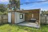 Detached structure featuring a covered wood-decked patio, horizontal wood slat privacy wall, sliding barn-style door, and attached overhead string lig