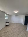 Interior space featuring neutral tile flooring, a wall-mounted mini-split HVAC system, a flush-mount circular light fixture, and a window with a horiz