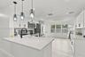 Kitchen featuring white cabinetry, solid-surface countertops, stainless steel appliances, a farmhouse-style sink with a matte black faucet, and glass 