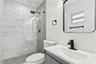 Bathroom featuring a glass-enclosed shower with marbled tile, a rain-style showerhead, wood-finish wall tile accents, a vanity with a rectangular basi