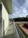 Elevated balcony featuring a painted wood-finish deck and white metal railings with water and horizon scenery