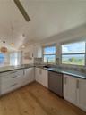 Kitchen featuring white shaker-style cabinetry, stone-finish countertops, stainless steel dishwasher, hexagonal tile backsplash, and wood-finish floor