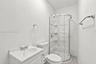 Bathroom featuring a corner shower enclosure with a molded surround, white pedestal vanity with dual-handle faucet, and chrome hardware throughout