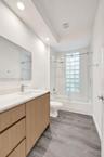 Wood-finish cabinetry with a solid surface countertop, recessed lighting, glass block window, sliding glass shower door, and gray wood-finish flooring