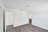 Room featuring wood-finish flooring, white walls, and a multi-directional ceiling light fixture