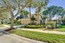Two-story residence featuring a stucco exterior, integrated two-car garage, manicured landscaping with mature palm trees, and a concrete paver drivewa