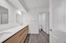 Bathroom featuring a long wood-finish vanity with a solid-surface countertop, dual undermount sinks, wall-mounted rectangular mirrors, and wood-finish