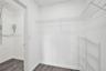 Walk-in storage area featuring wood-finish flooring and integrated white wire shelving systems