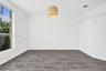 Neutral interior featuring wood-finish flooring, a large multi-pane window, and a drum-style pendant light fixture