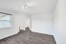 Interior space featuring wood-finish flooring, white walls, and a multi-bulb flush-mount ceiling fixture
