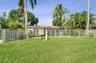 Rear exterior featuring a tile roof, stucco siding, a fenced-in yard, and mature palm trees