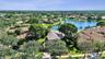 Aerial perspective of a residential neighborhood featuring tiled rooflines, mature landscaping, expansive green spaces, and an integrated freshwater l