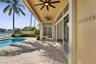 Covered patio with stone-paver flooring, dual ceiling fans, sliding glass doors, and a swimming pool
