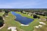 Aerial perspective of a golf course featuring expansive fairways, a central water hazard, sand bunkers, and mature perimeter landscaping