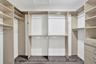 Custom walk-in closet featuring extensive built-in shelving, integrated hanging rods, and a multi-drawer storage unit with wood-finish flooring