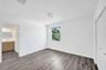 Neutral-toned interior space featuring wood-finish flooring, a double-door closet with paneled hardware, a single-light window, and modern multi-direc