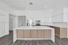 Kitchen featuring a large central island with a solid surface countertop, dual-tone cabinetry, stainless steel appliances, and wood-finish flooring