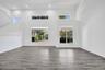 High-ceilinged interior space featuring wood-finish flooring, multi-level windows, and recessed lighting