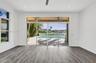 Wood-finish flooring, recessed lighting, ceiling fan, expansive sliding glass doors, and water-front swimming pool