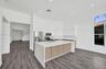 Kitchen featuring a large waterfall-edge center island, quartz countertops, dual-tone cabinetry, stainless steel appliances, and wood-finish flooring