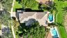 Aerial perspective featuring a multi-hipped tile roof, an in-ground swimming pool, a separate in-ground spa, mature trees, and manicured landscaping