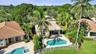 Stucco exterior residence featuring a tile roof, private swimming pool, patio area, and mature landscaping