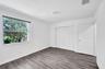 Room featuring wood-finish flooring, a multi-panel interior door, a floor-to-ceiling closet with bifold doors, and a single-pane window