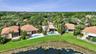 Aerial perspective of residential properties featuring tile roofs, private swimming pools, screened lanais, and water frontage