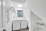 Laundry area featuring wood-finish flooring, white cabinetry, wire shelving, and vertical window blinds