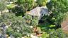 Two-story residence featuring a hipped tile roof, stucco exterior, paved driveway, mature landscaping, and a manicured lawn