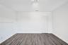 Neutral-toned interior space featuring wood-finish flooring, white walls, and a multi-panel bi-fold closet door