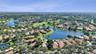 Aerial perspective of a property featuring a tile roof, mature landscaping, and positioning along a lakefront