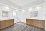 Dual wood-finish vanities with solid-surface countertops, integrated sinks, glass block window, and recessed ceiling lighting