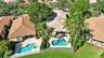 Aerial view of two residences featuring concrete tile roofing, paved pool decks, private swimming pools, and integrated spas, surrounded by mature pal