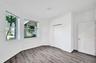 Room featuring wood-finish flooring, dual windows, ceiling-mounted light fixture, and two panel doors
