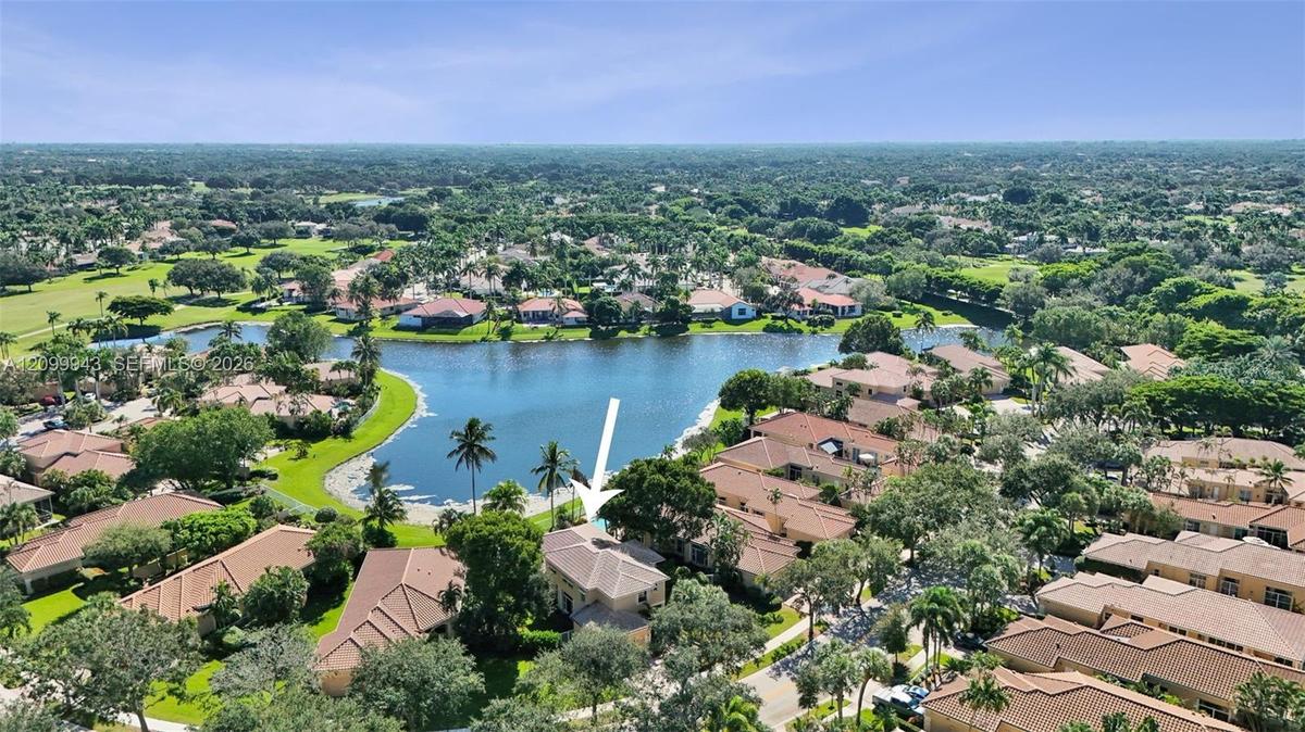 Aerial perspective of the residence featuring a multi-pitched tile roof, positioned on a waterfront lot with expansive water frontage and mature lands