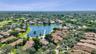 Aerial perspective of the residence featuring a multi-pitched tile roof, positioned on a waterfront lot with expansive water frontage and mature lands