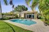 In-ground swimming pool with built-in stairs, concrete paver patio, stucco exterior, and multi-panel sliding glass doors