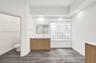 Wood-finish cabinetry with a white surface, rectangular wall-mounted mirror, glass block window, recessed lighting, and wood-finish flooring