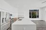 Kitchen featuring a quartz-topped center island with an undermount sink, stainless steel appliances, flat-panel cabinetry, and wood-finish flooring