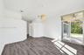 Open interior featuring wood-finish flooring, recessed lighting, a cylindrical pendant fixture, and glass sliding doors