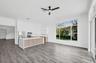 Open-concept interior featuring wood-finish flooring, recessed lighting, a ceiling fan, and a kitchen island with white countertop and wood-finish cab