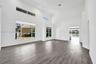 High-ceiling living area featuring wood-finish flooring, multi-level windows, and recessed lighting