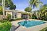 In-ground swimming pool with paver decking, covered patio, tile roof, and mature landscaping