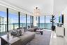 Framed by floor-to-ceiling impact glass, the living room opens seamlessly onto the wraparound balcony, creating an inviting retreat to unwind while en