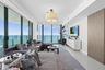 Framed by floor-to-ceiling impact glass, the living room opens seamlessly onto the wraparound balcony, creating an inviting retreat to unwind while en