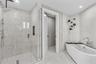 A private spa within the primary suite, this exquisite bathroom showcases custom porcelain tile, a frameless glass shower, a freestanding soaking tub 