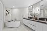 A private spa within the primary suite, this exquisite bathroom showcases custom porcelain tile, a frameless glass shower, a freestanding soaking tub 