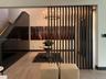 Vertical slatted room divider, wood-finish flooring, high-gloss paneled accent wall, and multi-arm chandelier