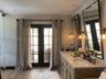 Dual-sink vanity with a stone countertop, recessed lighting, wood-finish flooring, and black-framed glass-paneled double doors